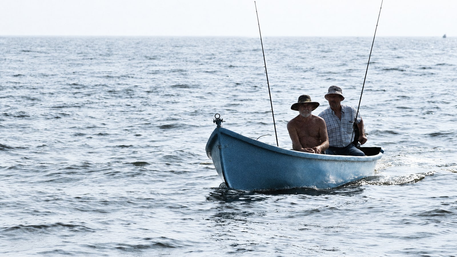 Anglers in a small boat on the open sea in low light