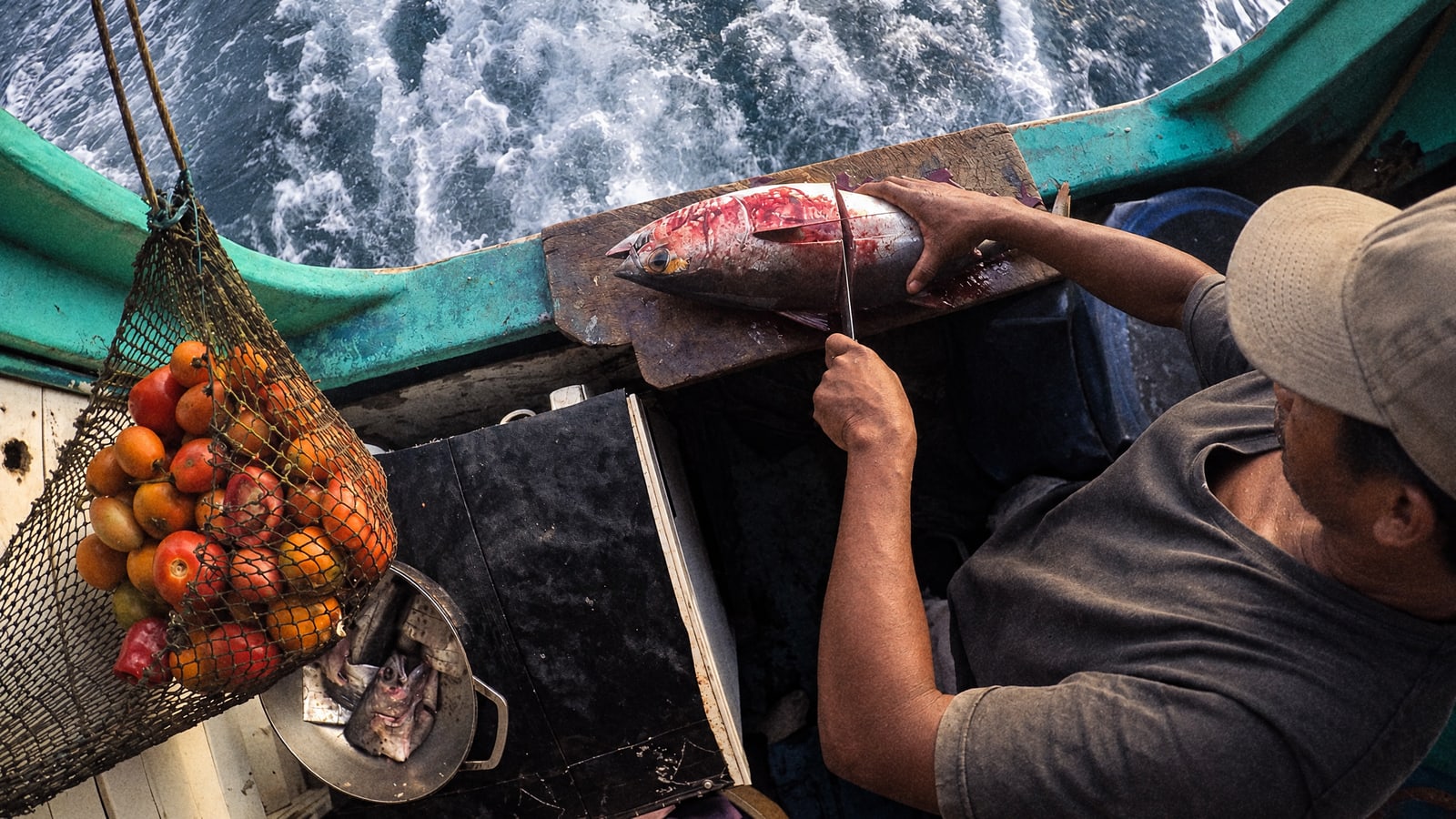 A fisherman preparing the catch on board with the sea behind