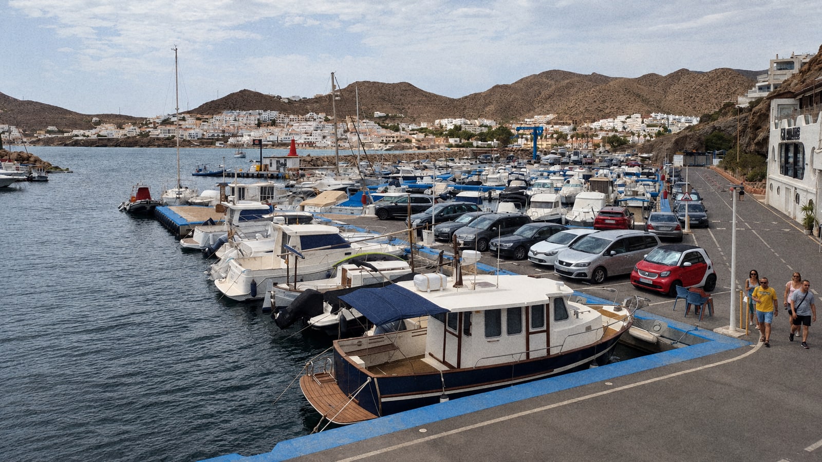 Boats tied up in a small Andalusian marina under a cloudy, breezy sky, the trip waiting for the wind to drop