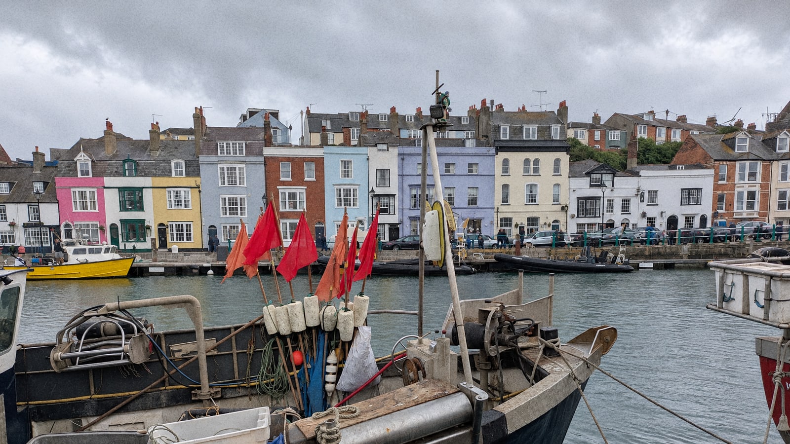 Small fishing boats tied up in an English harbour under a grey sky, the trip postponed for the weather