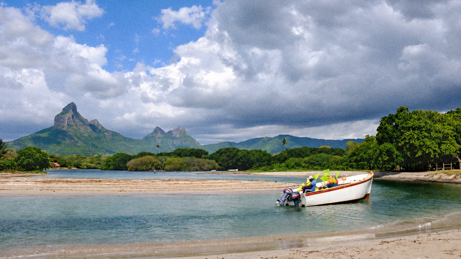 A small boat pulled up in a Mauritius lagoon under the mountains