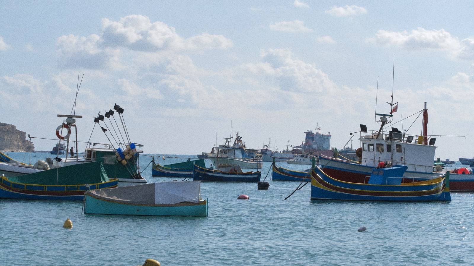 Fishing boats moored in Marsaxlokk harbour, Malta, under a grey winter sky