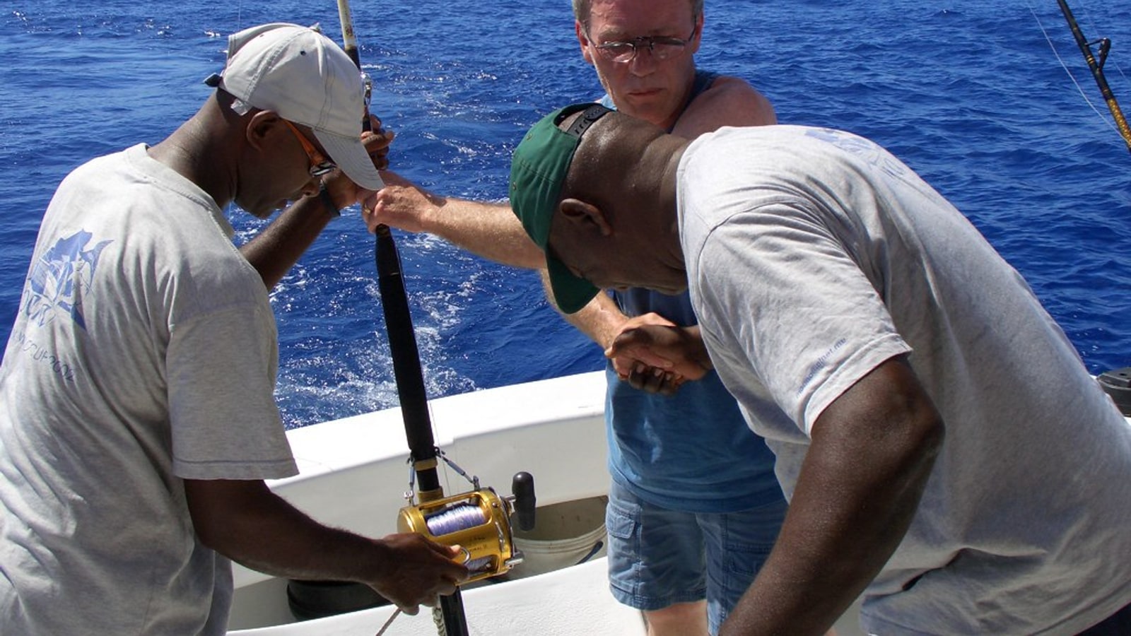 Crew helping a guest with the rod on a fishing boat off Mauritius