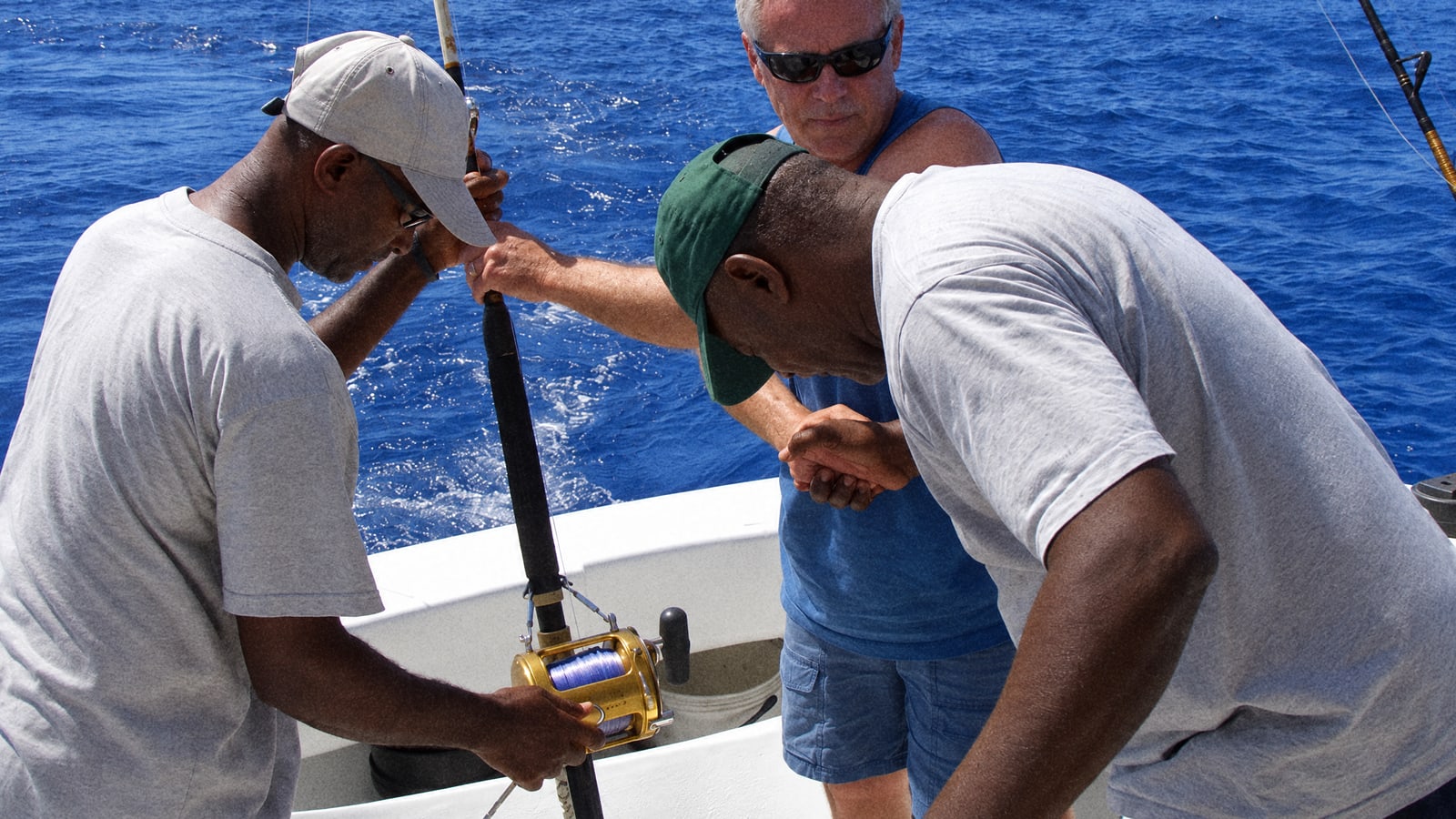 A deckhand and a guest working the rods on a sportfishing boat